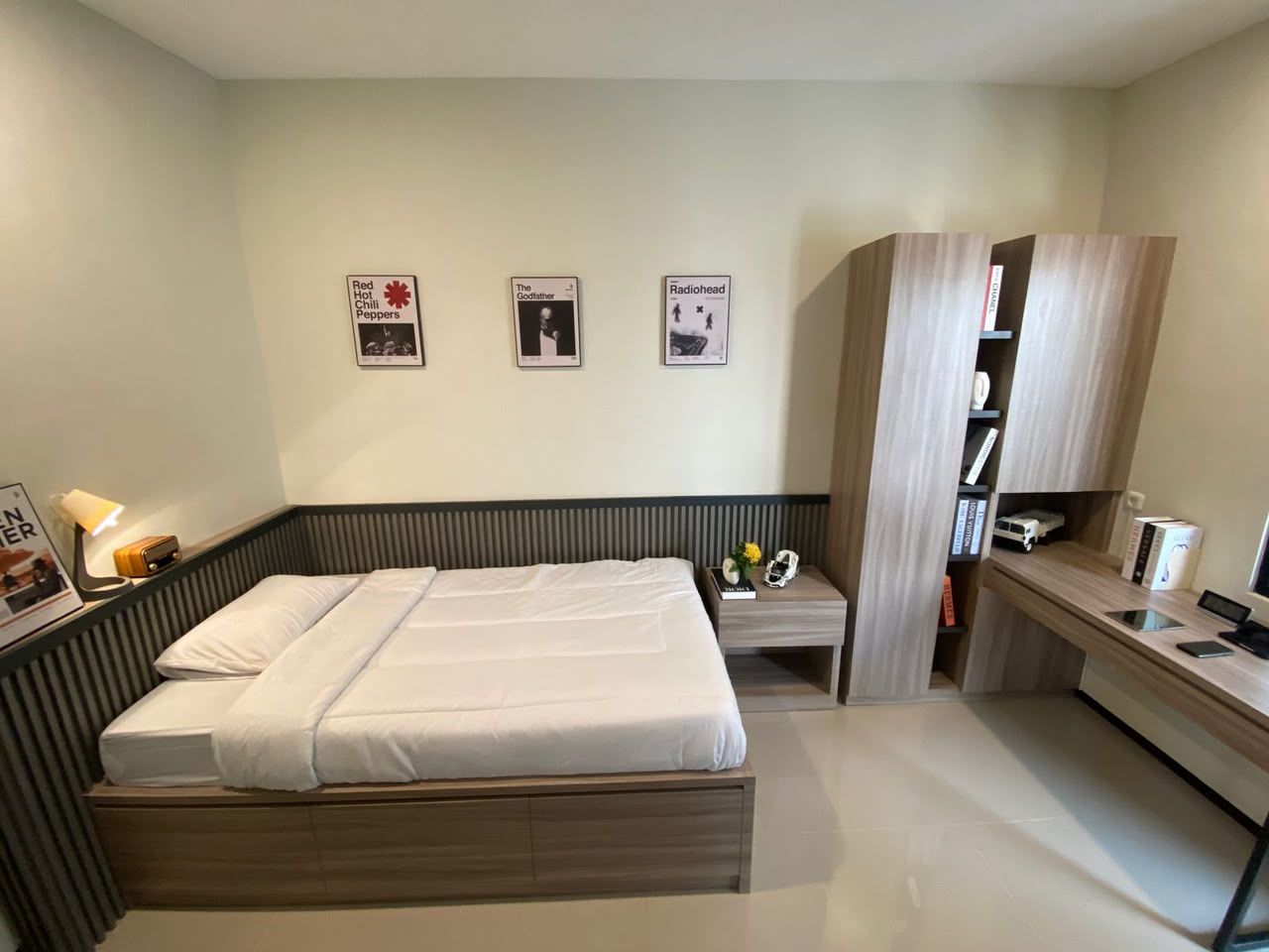 Contoh kamar: kasur putih, wainscot bilah kayu abu gelap, lemari dan meja kerja kayu oak, dinding krem sage dengan tiga poster berbingkai